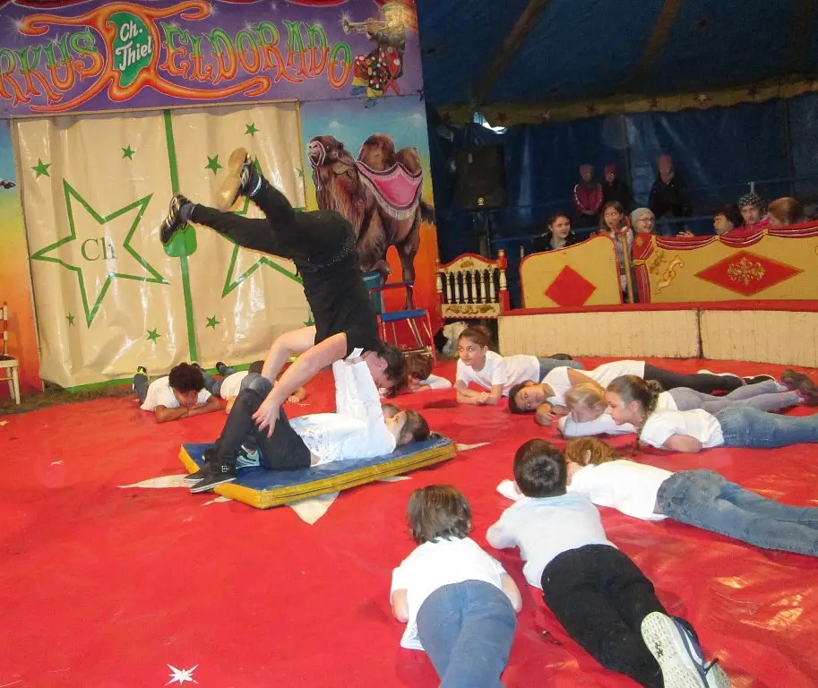 Akrobatik-zwei Kinder stemmen einen Mann